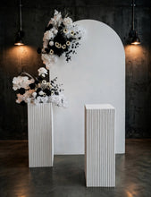 Load image into Gallery viewer, White arch backdrop, 2 x black & white flowers, 2 x white square ripple plinths - HIRE ONLY