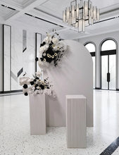 Load image into Gallery viewer, White arch backdrop, 2 x black & white flowers, 2 x white square ripple plinths - HIRE ONLY