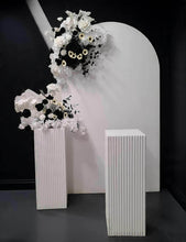 Load image into Gallery viewer, White arch backdrop, 2 x black &amp; white flowers, 2 x white square ripple plinths - HIRE ONLY
